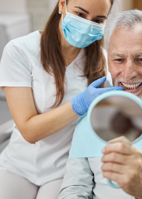 Dental patient looking in mirror, admiring his new bridge