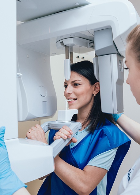 a dental assistant taking a scan of a patient’s mouth using a cone beam CT scanner