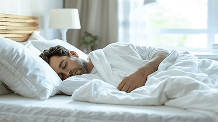 Man sleeping peacefully in white bedsheets