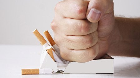 Man crushing a carton of cigarettes