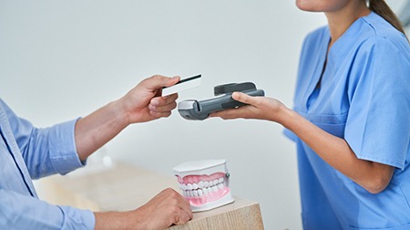 An obscured patient paying for their dental emergency care