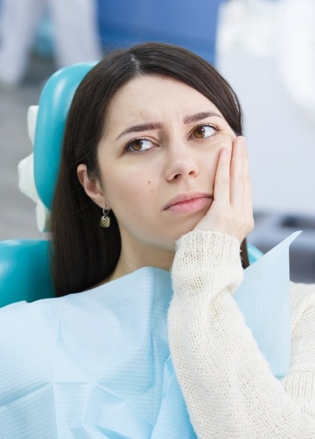 Woman frowning in dental chair before getting dental implant dentures in Tampa