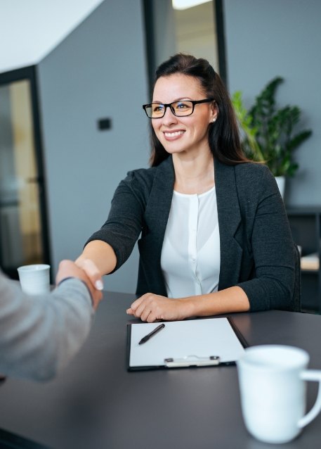 Woman shaking hands with person sitting across table