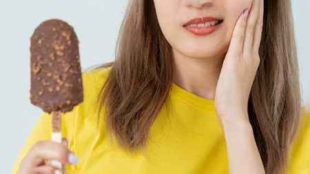 Woman holding ice cream and rubbing her jaw