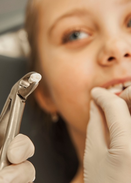 Dentist holding a clasp with a tooth next to a patient